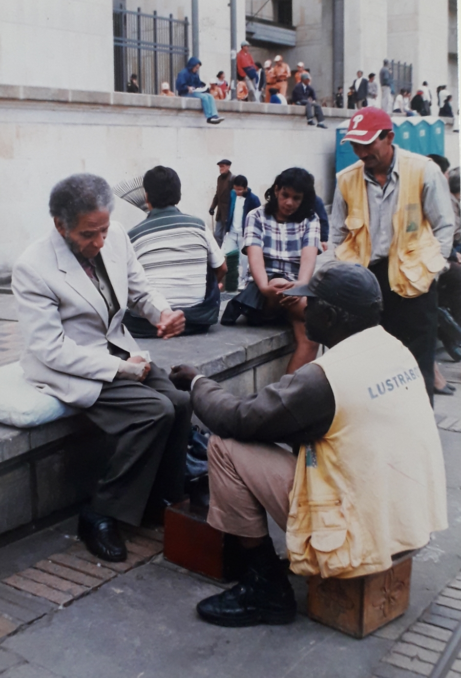 Manuel Zapata Olivella en la Plaza de Bolívar de Bogotá, mientras le lustran sus zapatos.